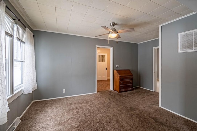 empty room with crown molding, ceiling fan, a wealth of natural light, and dark colored carpet