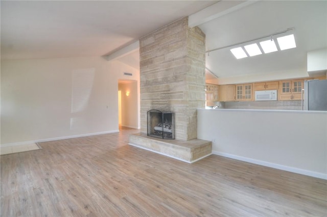 unfurnished living room featuring baseboards, lofted ceiling with beams, wood finished floors, and a fireplace