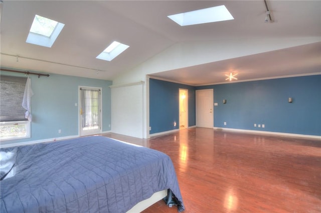 bedroom with baseboards, rail lighting, wood finished floors, and vaulted ceiling with skylight