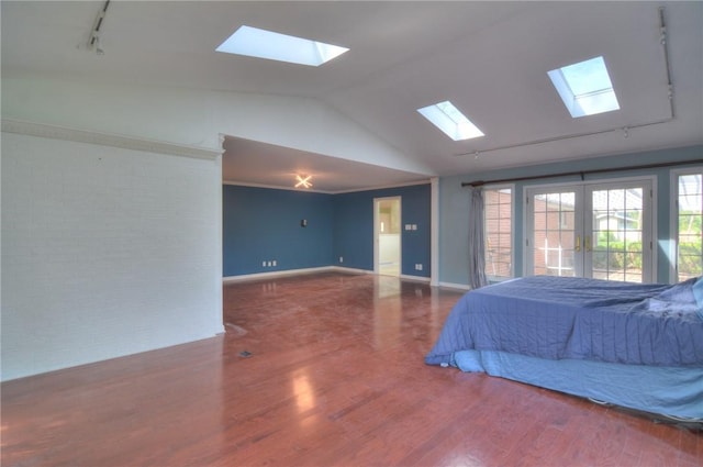 bedroom featuring track lighting, brick wall, access to exterior, vaulted ceiling with skylight, and french doors
