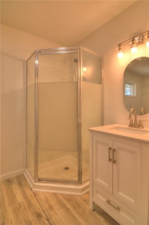 full bathroom with vanity, wood finished floors, and a stall shower