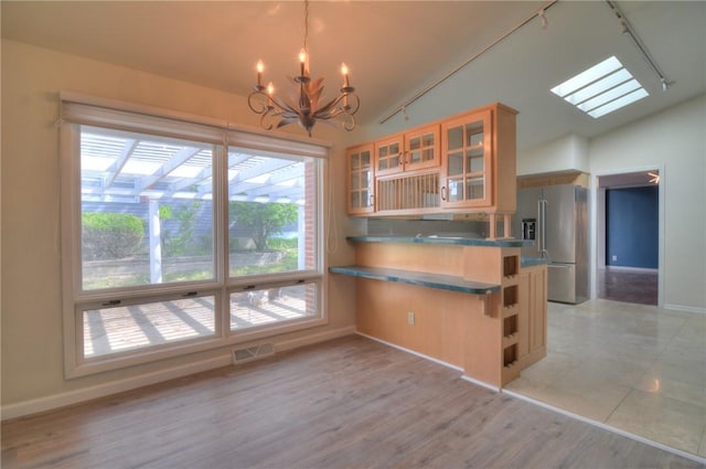 kitchen with a notable chandelier, track lighting, visible vents, stainless steel refrigerator with ice dispenser, and vaulted ceiling