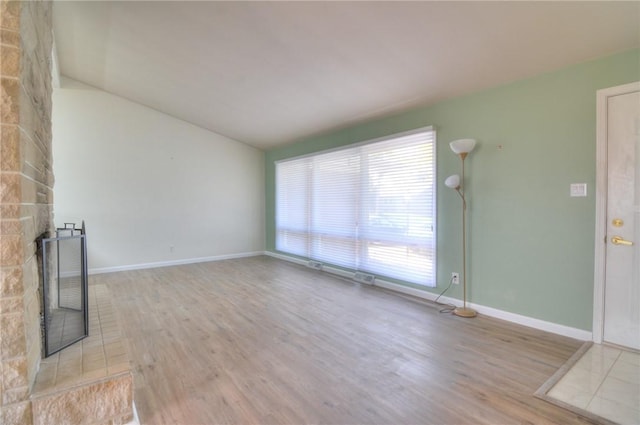 unfurnished living room featuring baseboards, wood finished floors, and lofted ceiling
