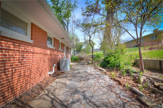 view of property exterior featuring central AC unit, a patio area, and brick siding