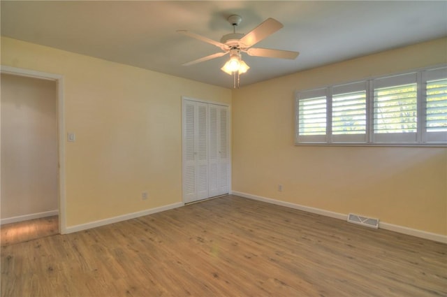 unfurnished bedroom featuring baseboards, wood finished floors, and visible vents