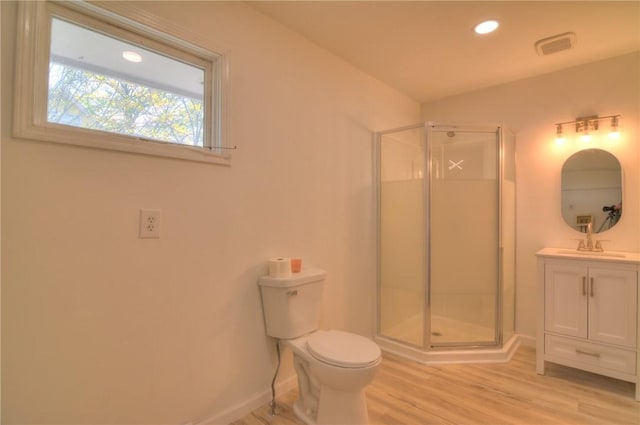bathroom with vanity, toilet, baseboards, a shower stall, and wood finished floors