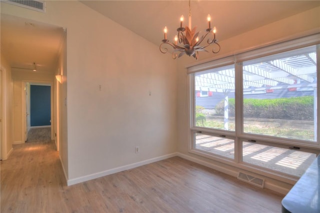 unfurnished dining area with an inviting chandelier, light wood-style flooring, a healthy amount of sunlight, and visible vents