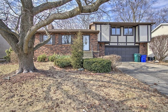 tri-level home featuring a garage, brick siding, driveway, and a chimney