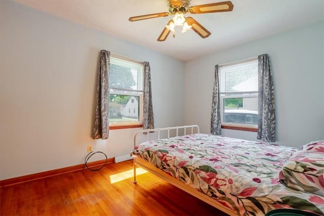 2417 Maple Ave, Decatur, IL 62526 - bedroom featuring multiple windows, wood finished floors, a ceiling fan, and radiator heating unit