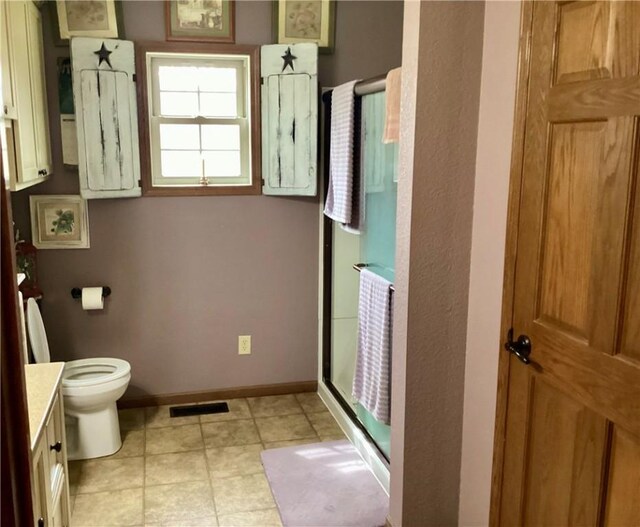 bathroom featuring vanity, baseboards, toilet, a shower stall, and visible vents