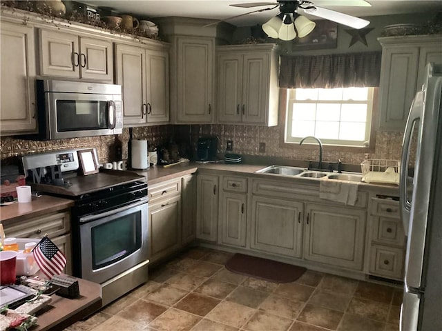 kitchen featuring decorative backsplash, a sink, a ceiling fan, and stainless steel appliances