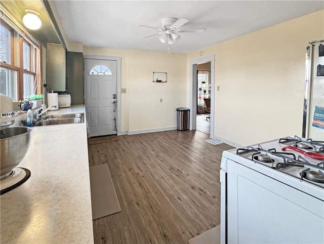 kitchen featuring dark wood-style floors, light countertops, a sink, and white gas range