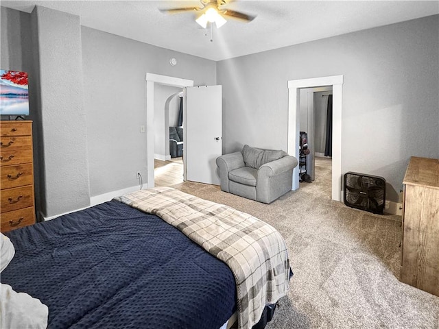 bedroom with a ceiling fan, light colored carpet, and baseboards