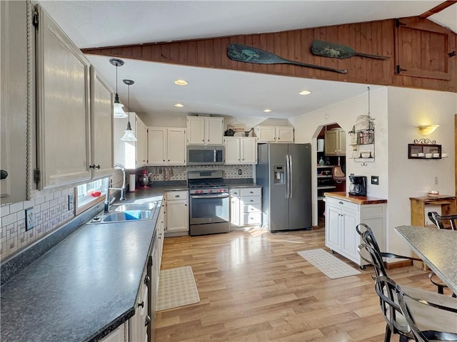 kitchen featuring lofted ceiling, stainless steel appliances, arched walkways, and a sink