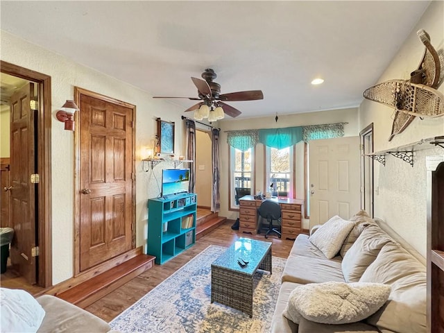 living area featuring a textured wall, wood finished floors, a ceiling fan, and recessed lighting