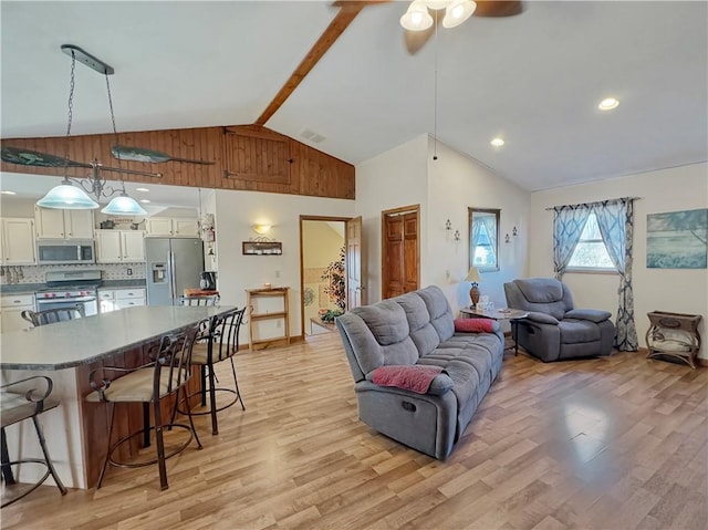 living room with visible vents, a ceiling fan, light wood-style flooring, beamed ceiling, and high vaulted ceiling