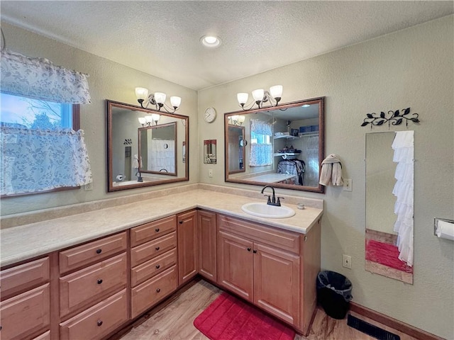 bathroom with a textured wall, vanity, a textured ceiling, and wood finished floors