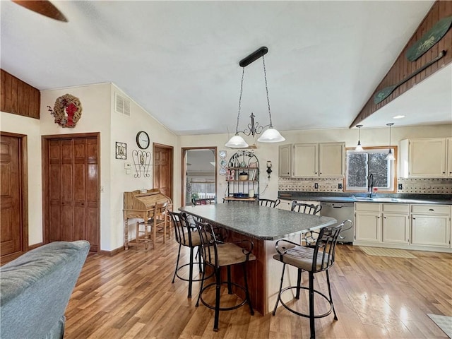 kitchen featuring dishwasher, dark countertops, lofted ceiling, and light wood-style floors