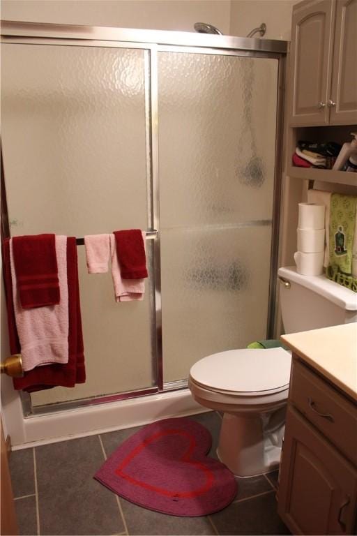 bathroom featuring tile patterned flooring, toilet, vanity, and walk in shower