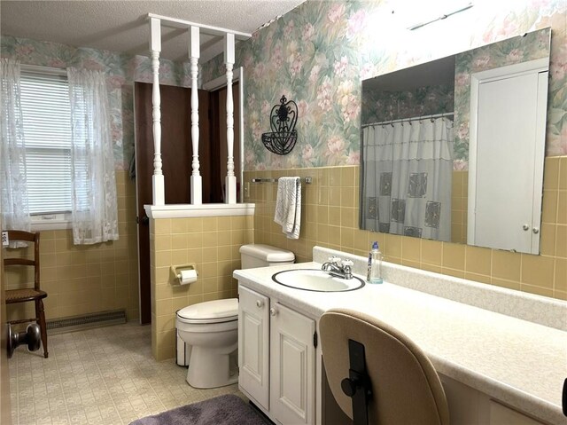 601 Holiday Dr, Effingham, IL 62401 - bathroom featuring wallpapered walls, tile walls, vanity, wainscoting, and a textured ceiling
