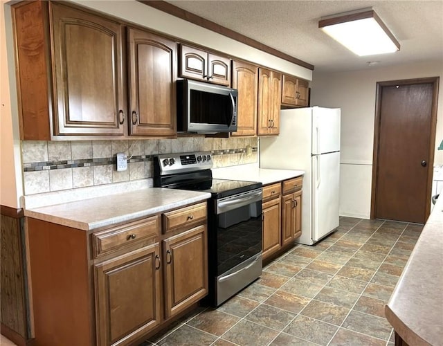 601 Holiday Dr, Effingham, IL 62401 - kitchen with appliances with stainless steel finishes, decorative backsplash, light countertops, dark stone finish floors, and a textured ceiling