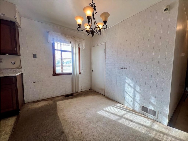 unfurnished dining area featuring an inviting chandelier, carpet, and brick wall