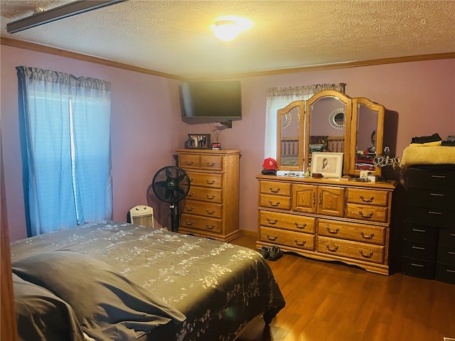 bedroom featuring hardwood / wood-style flooring, ornamental molding, and a textured ceiling