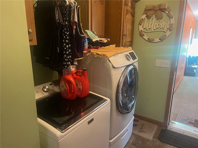 laundry room featuring washer and dryer, light tile patterned flooring, and cabinets