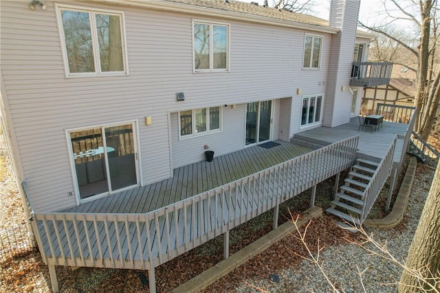 back of property with stairs, a chimney, and a wooden deck