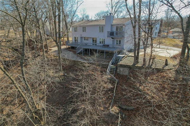 back of house with stairway, a chimney, and a wooden deck