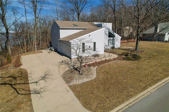 view of side of home with driveway, a garage, and a lawn