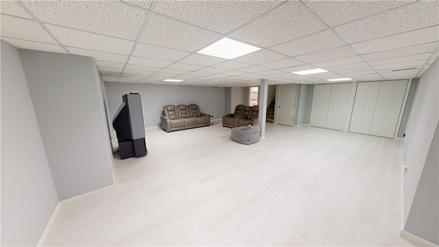 finished basement featuring wood finished floors, a paneled ceiling, and baseboards