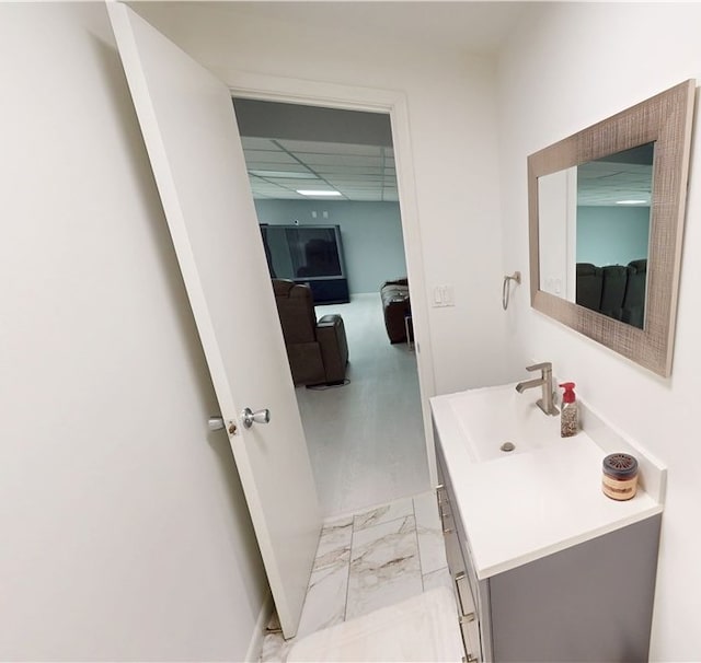 bathroom with marble finish floor, a drop ceiling, and vanity