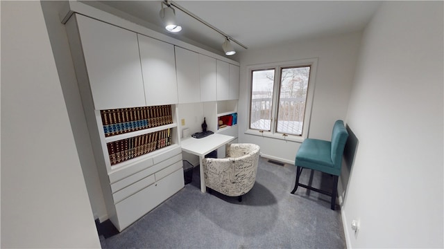 living area featuring baseboards, visible vents, dark colored carpet, and track lighting