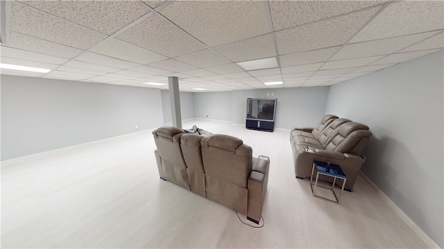 living area with a paneled ceiling, light wood-style flooring, and baseboards