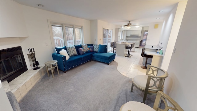 living room with a fireplace, light tile patterned floors, recessed lighting, light carpet, and ceiling fan