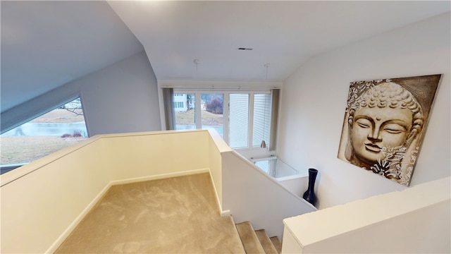 hall featuring vaulted ceiling, a wealth of natural light, light carpet, and an upstairs landing