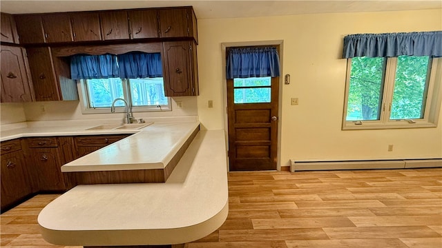 kitchen featuring plenty of natural light, light hardwood / wood-style floors, sink, and a baseboard heating unit