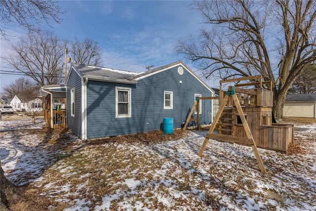 snow covered property featuring a playground and a chimney