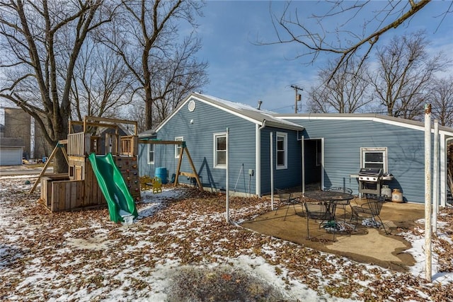snow covered property featuring a patio and a playground