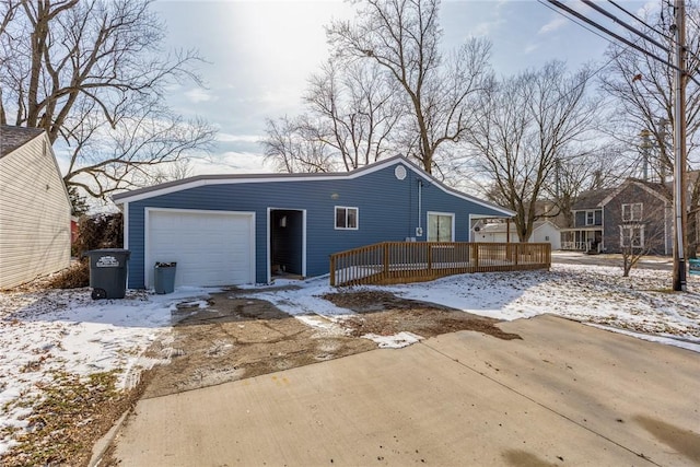 snow covered rear of property featuring an attached garage and a deck