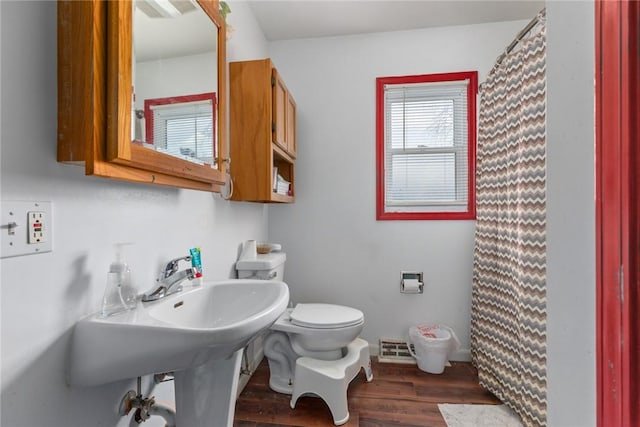 bathroom featuring toilet, wood finished floors, a shower with curtain, and visible vents