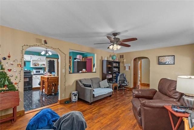 living area with visible vents, arched walkways, wood finished floors, and ceiling fan with notable chandelier