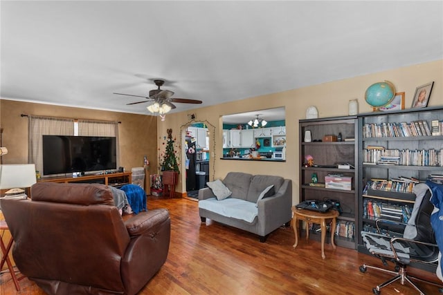 living area featuring wood finished floors and ceiling fan with notable chandelier