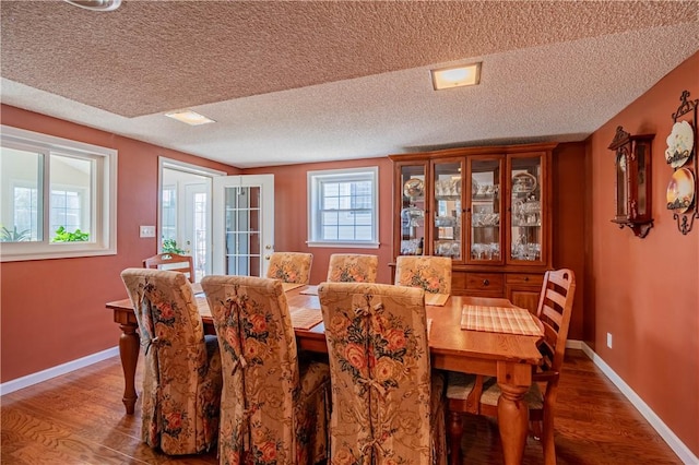 dining room featuring baseboards, a textured ceiling, and wood finished floors