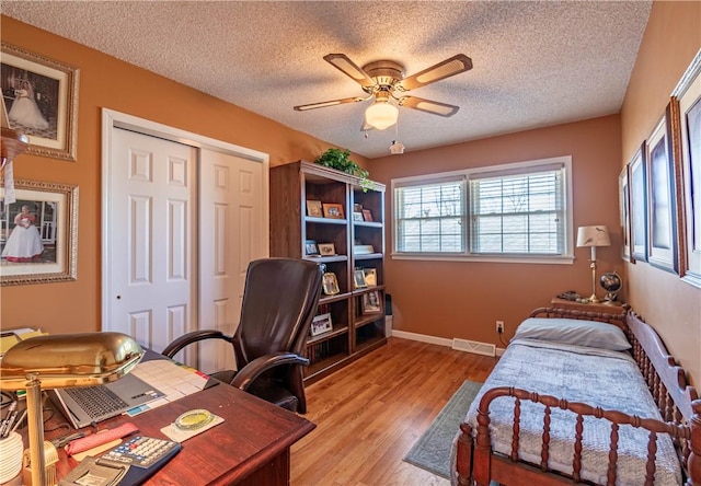 bedroom featuring visible vents, baseboards, light wood-style floors, a closet, and a textured ceiling