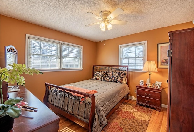 bedroom featuring a ceiling fan, wood finished floors, baseboards, and a textured ceiling