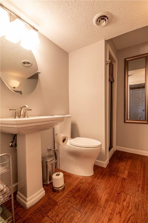 bathroom featuring visible vents, toilet, wood finished floors, and a textured ceiling