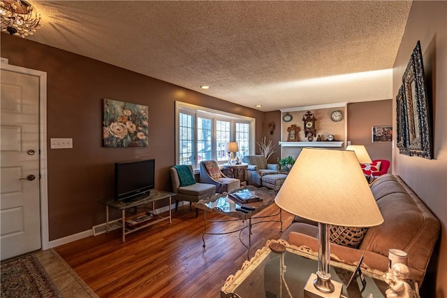 living area featuring baseboards, a textured ceiling, and wood finished floors