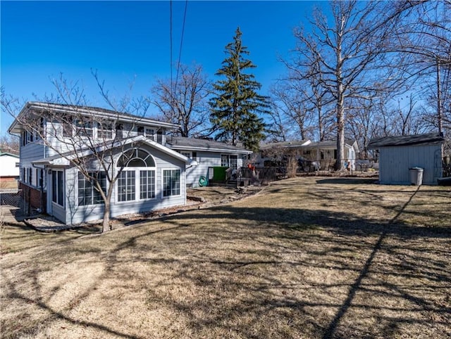 back of house featuring an outbuilding, a yard, fence, and a shed